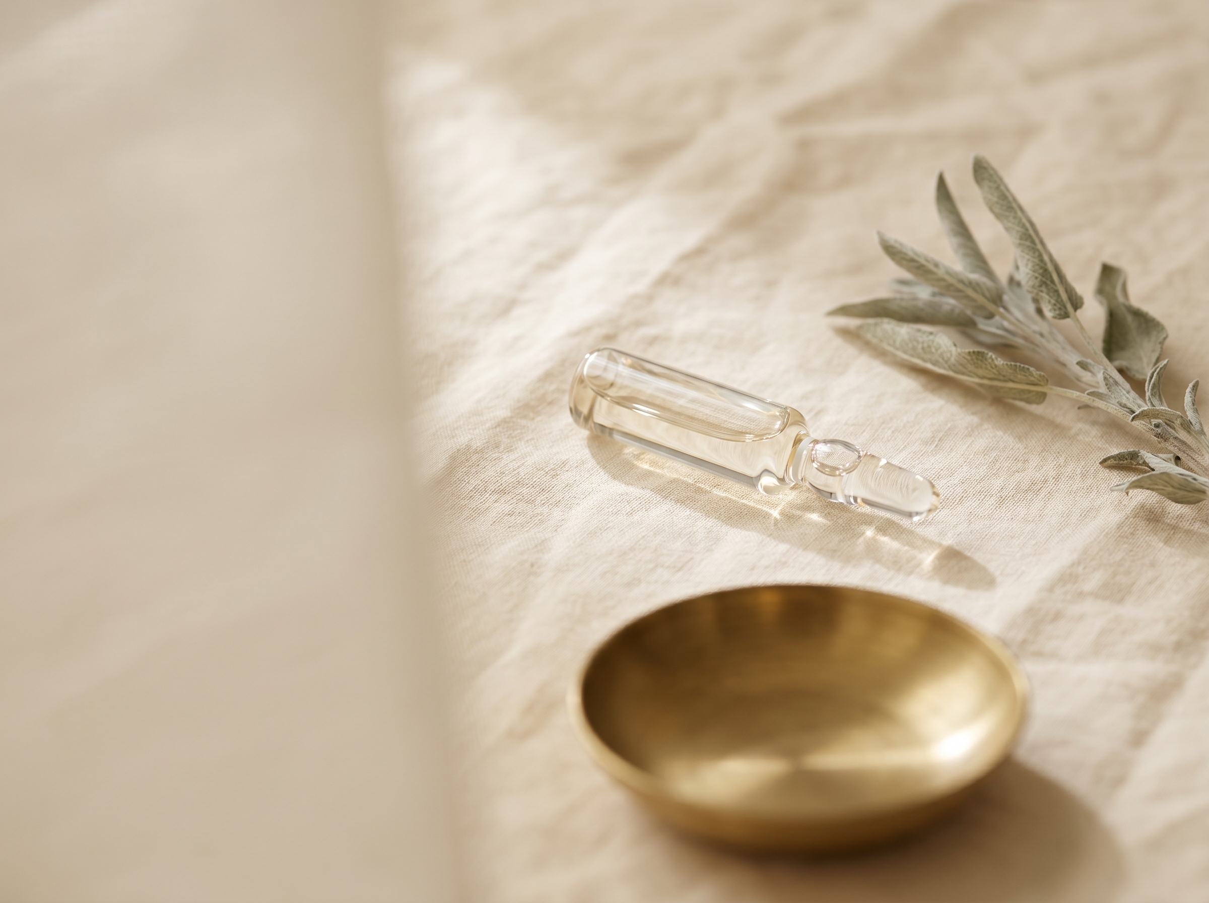 A sealed pharmaceutical-grade clear-glass apothecary ampoule on cream linen with a sprig of dried sage and a small brushed-brass dish — Aesura Health's physician-supervised neurotoxin (Jeuveau, Letybo) practice in Hackensack, Bergen County NJ.